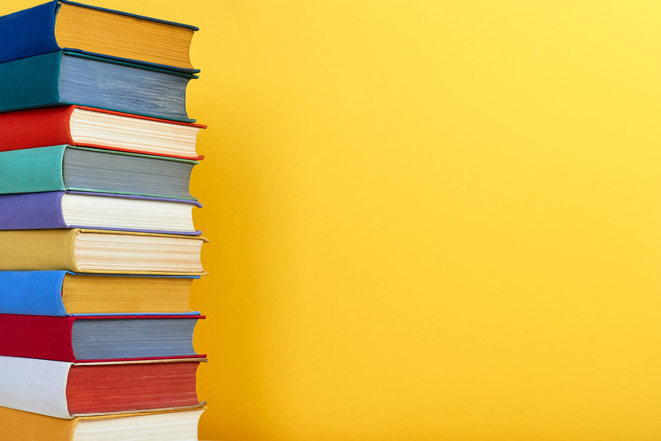 Multicolored books stack over yellow background